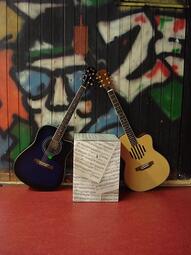 Vergrößerte Ansicht von Zwei akustische Gitarren vor einer mit Graffiti besprühten Wand