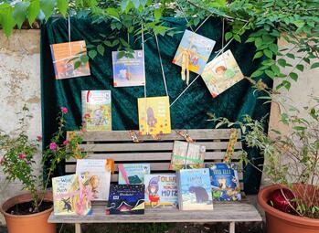 Vergrößerte Ansicht von Kinderbücher stehen auf einer Gartenbank.