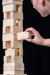 Vergrößerte Ansicht von Ein Baustein wird in ein Holzbausteingerüst geschoben.