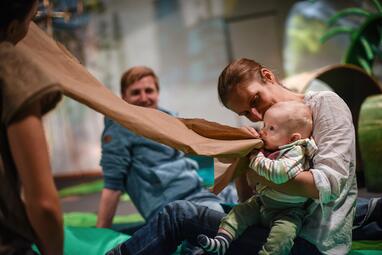 Vergrößerte Ansicht von Ein Baby spielt mit einem Elternteil an einem großen Papierstück.