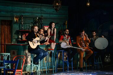 Vergrößerte Ansicht von Nicolas Fethi Türksever, Annemarie Brüntjen und Musiker sitzen an einer Bar.