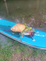 Vergrößerte Ansicht von Das Foto zeigt den im Wasser durch die Kanugesellschaft Neckaru gesammelten Müll. Der Müll liegt auf einem Stand-Up-Paddle-Board, zu sehen sind hier Plastikflaschen, Getränkedosen und vermutlich Bauschutt.