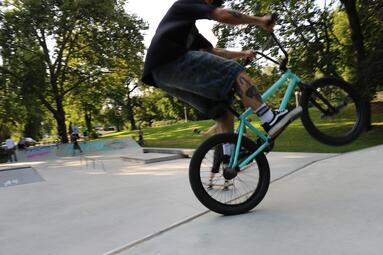 Vergrößerte Ansicht von Skatepark Schnickenloch, Lindenhof: Person auf einem BMX-Bike auf einer Rampe, im Hintergrund ein Park