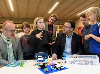 Schüler aus der Lego-AG der Franklinschule erklären den Bürgermeistern, wie sie ihre bunten Bausteine digital steuern.