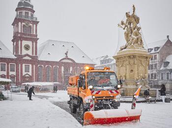 Winterdienstfahrzeug beim Schneeschieben auf dem Marktplatz