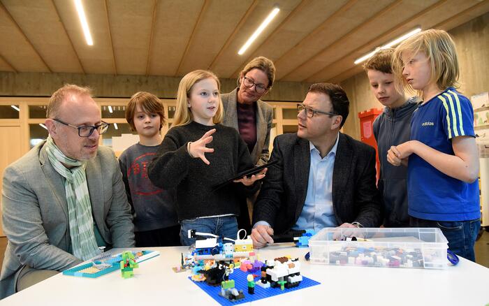 Schüler aus der Lego-AG der Franklinschule erklären den Bürgermeistern, wie sie ihre bunten Bausteine digital steuern.